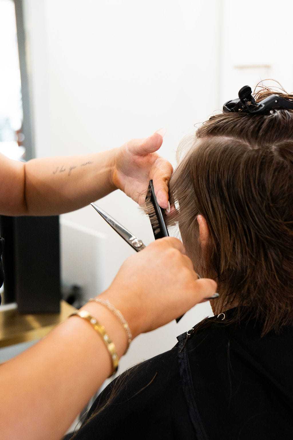 Hairdresser cutting client's hair with scissors in a salon.