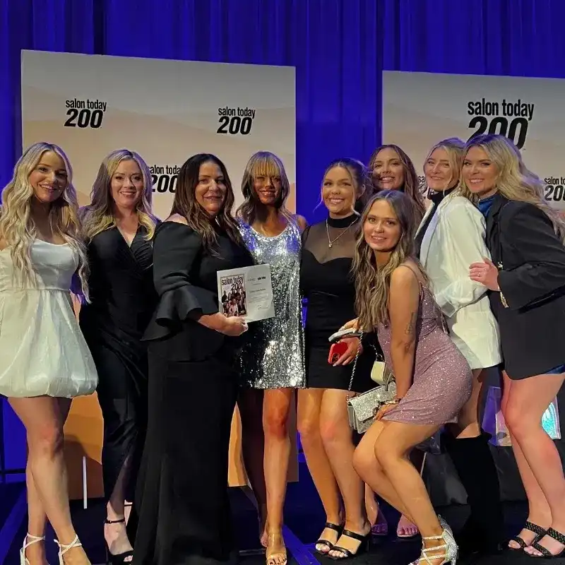 Group celebrates award at Salon Today 200 event with smiling poses and stylish outfits.